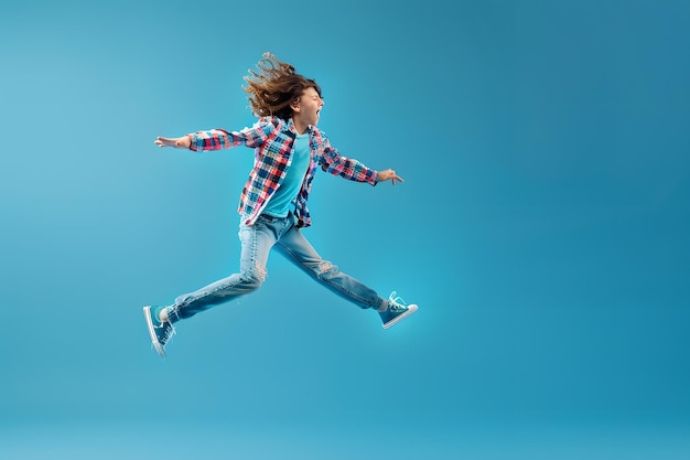 Foto volledig portret van een vrolijke kleine jongen die geïsoleerd over een blauwe achtergrond springt