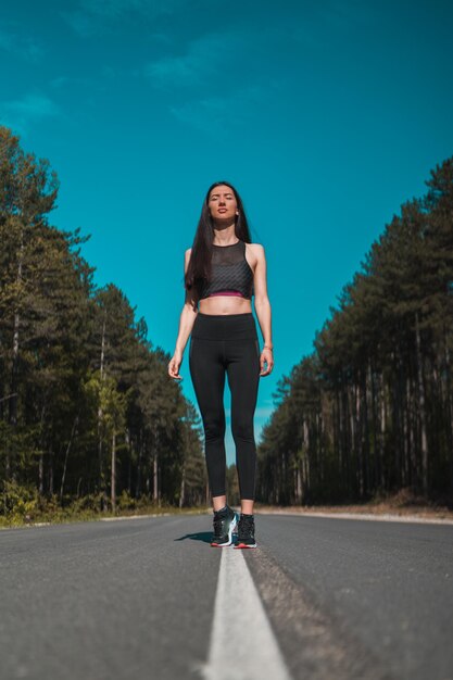 Volledig portret van een vrouw op de weg tegen bomen