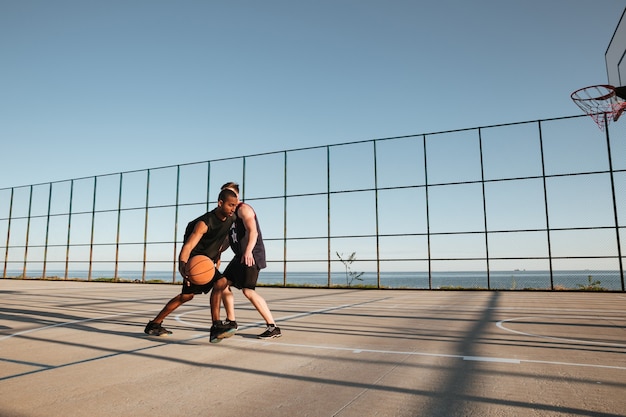 Volledig portret van twee sporters die basketbal spelen op de speelplaats