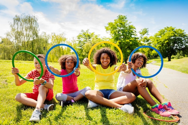 Foto volledig portret van vrienden die plastic ringen vasthouden terwijl ze op het gras zitten