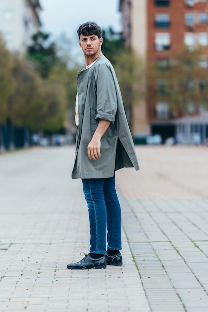 Volledig shot van een portret van een volwassen man die achter zijn rug om op straat kijkt