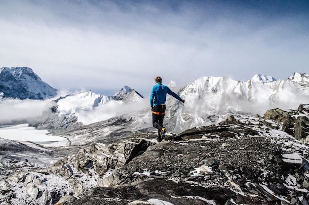 Volledige achtergrondbeeld van een man die op het landschap loopt door besneeuwde bergen tegen de lucht