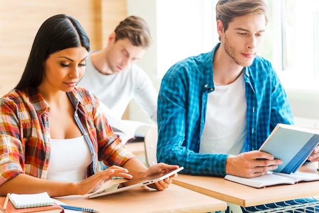 Volledige concentratie. drie geconcentreerde jonge studenten studeren terwijl ze aan hun bureau in de klas zitten