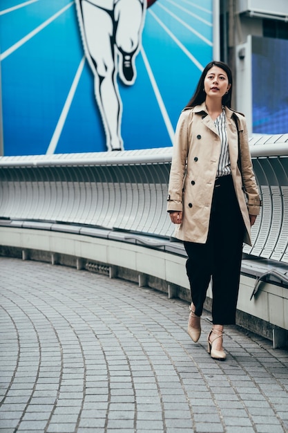 volledige lengte Aziatische vrouw die buiten in Osaka, Japan loopt. elegante zakenvrouw kantoormedewerker in het zakendistrict van de binnenstad. Jonge Chinese vrouwelijke professional bezoekt beroemde lopende man teken nippon.