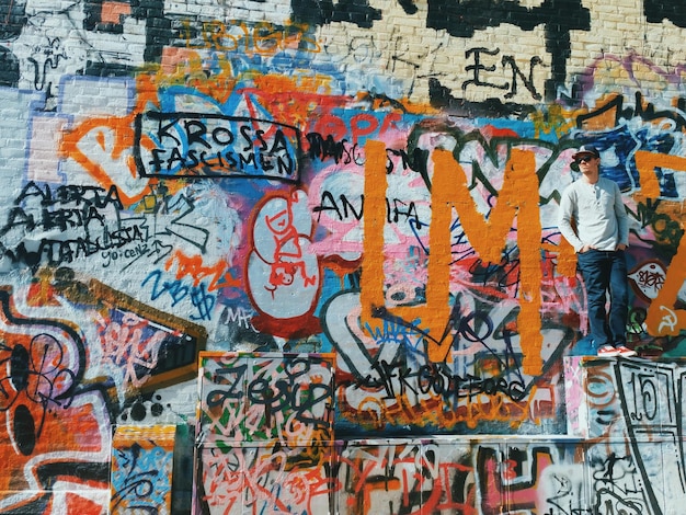 Foto volledige lengte op man die tegen graffiti op de muur staat