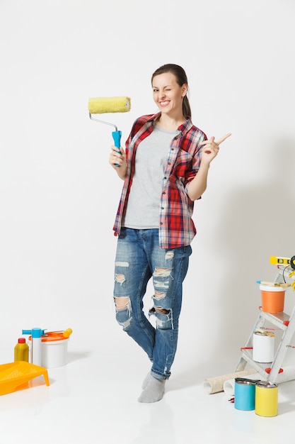 Volledige lengte portret van vrouw met verfroller permanent in de buurt van instrumenten voor renovatie appartement thuis geïsoleerd op een witte achtergrond. Behang, accessoires om te lijmen, tekengereedschappen. Reparatieconcept.