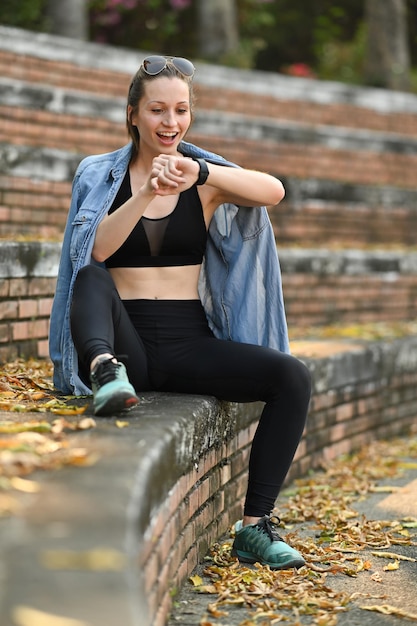 Volledige lengte van atletische vrouw die fitnessresultaten of hartslag controleert op smartwatch na hardlopen in het park