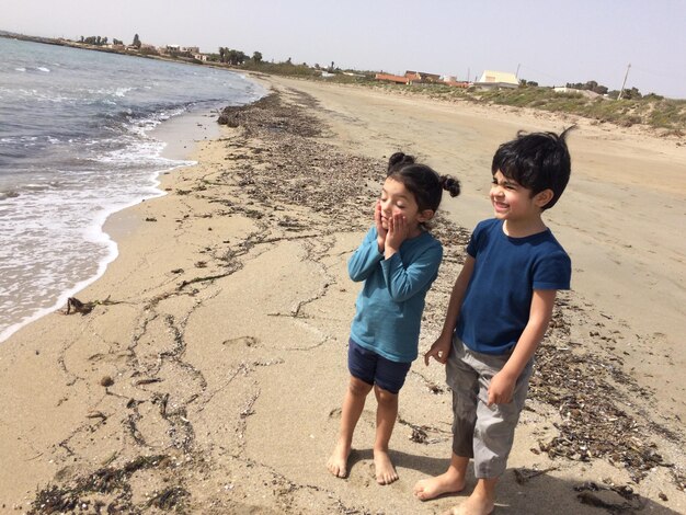 Foto volledige lengte van broers en zussen op het strand