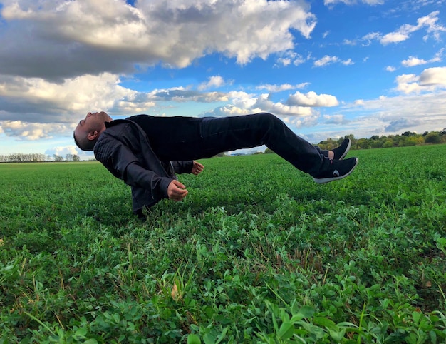 Foto volledige lengte van de man zweven op het veld tegen de lucht