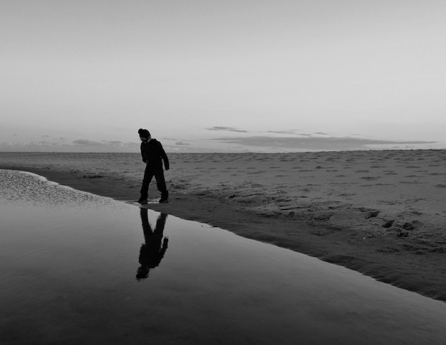 Volledige lengte van de mens op het strand tegen de hemel