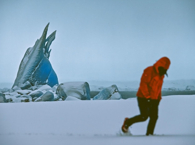 Volledige lengte van een man die in een met sneeuw bedekt veld tegen de hemel loopt