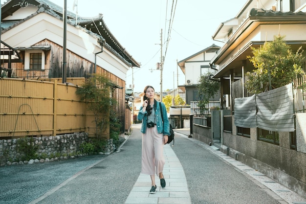 volledige lengte van elegante damereiziger die op steenrotsweg loopt in de stad kyoto japan. jong meisje backpacker ervaring Japanse lokale cultuur levensstijl staande in het midden van de straat rondkijken.