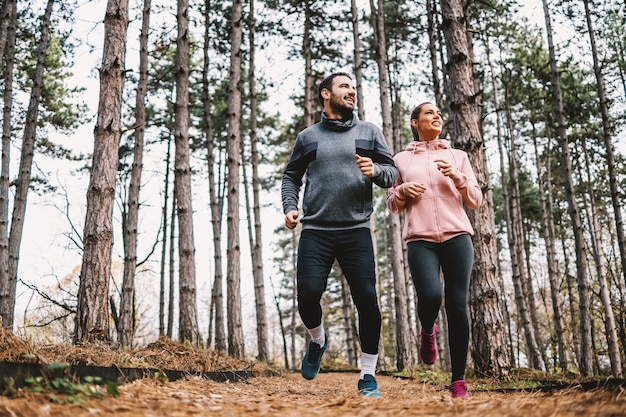 Volledige lengte van fit paar loopt door bos in de herfst en voorbereiding op de marathon.