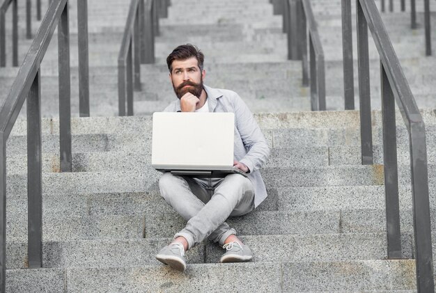 Volledige lengte van freelancer man heeft online laptopcommunicatie in de straat freelancer man