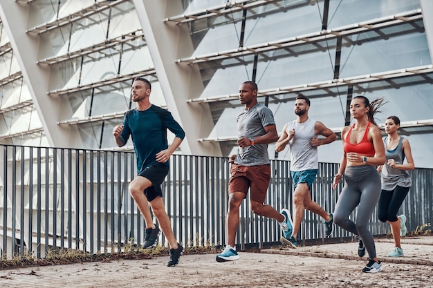 Volledige lengte van jonge mensen in sportkleding die joggen terwijl ze buiten sporten