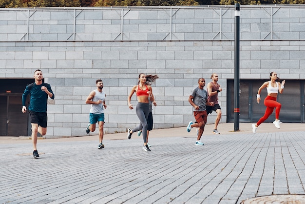 Volledige lengte van jonge mensen in sportkleding die joggen terwijl ze buiten sporten