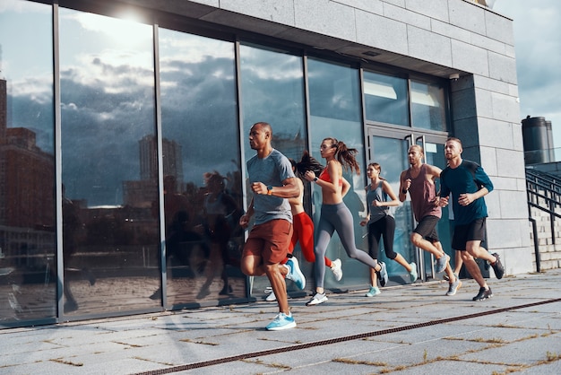 Volledige lengte van jonge mensen in sportkleding die joggen tijdens het sporten op het trottoir buitenshuis