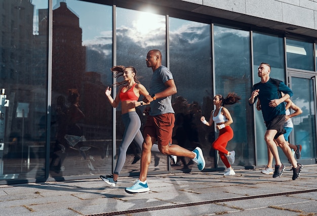 Volledige lengte van jonge mensen in sportkleding die joggen tijdens het sporten op het trottoir buitenshuis