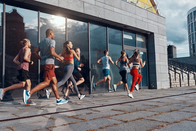 Volledige lengte van jonge mensen in sportkleding die joggen tijdens het sporten op het trottoir buitenshuis