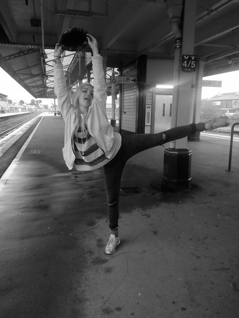 Foto volledige lengte van jonge vrouw die zich uitstrekt op het perron van het treinstation