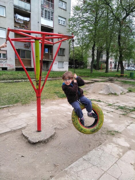 Foto volledige lengte van jongen op hangende band in het park