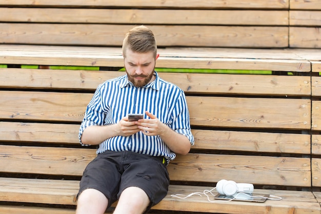 Volledige lengte van man die mobiele telefoon gebruikt terwijl hij op een bank zit