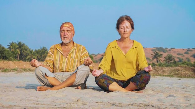 Foto volledige lengte van meditatie paar zit op het strand tegen de lucht