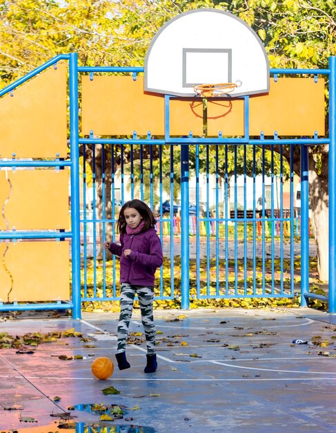 Volledige lengte van meisje met bal die op basketbalveld staat