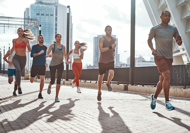 Volledige lengte van mensen in sportkleding die joggen terwijl ze buiten op het trottoir trainen