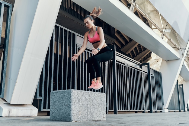 Volledige lengte van mooie jonge vrouw in sportkleding die buiten huppelt