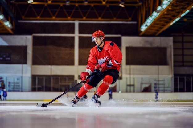 Volledige lengte van onverschrokken hockeyspeler die naar het doel schaatst en probeert een score te maken. hal interieur. wintersport.