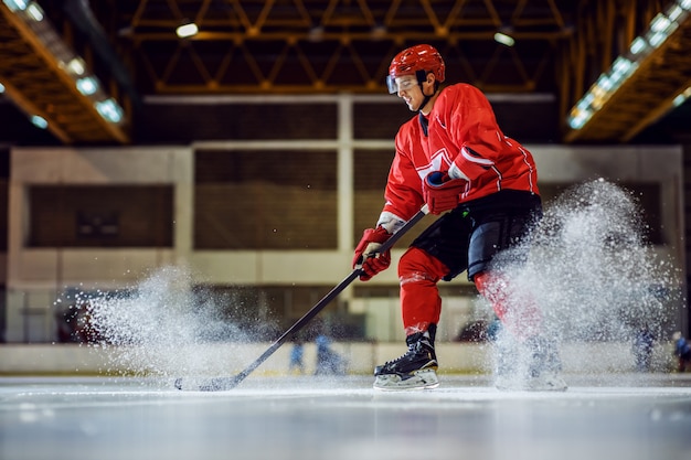 Foto volledige lengte van onverschrokken hockeyspeler die schaatst en probeert te scoren. hal interieur. wintersport.