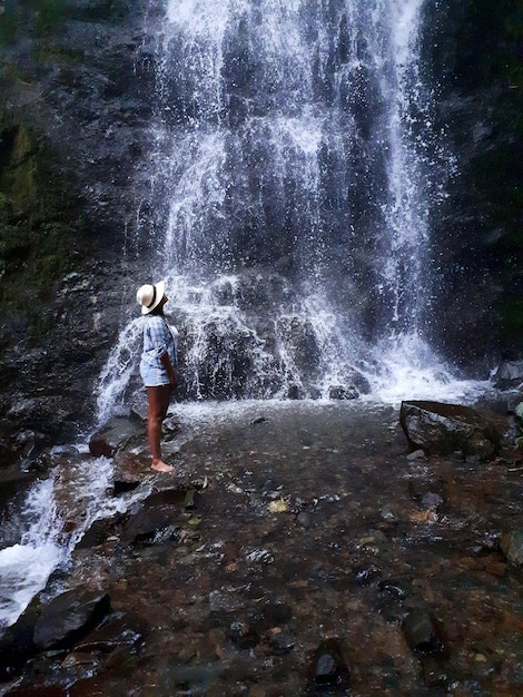Volledige lengte van vrouw die bij een waterval staat