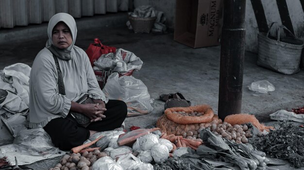 Foto volledige lengte van vrouw die groenten verkoopt op de marktstand