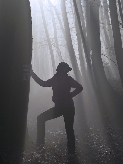 Foto volledige lengte van vrouw die in het bos staat tijdens mistig weer