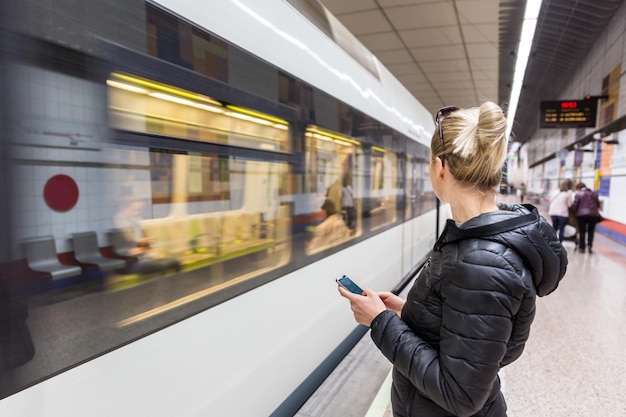 Foto volledige lengte van vrouw die mobiele telefoon gebruikt op het treinstation