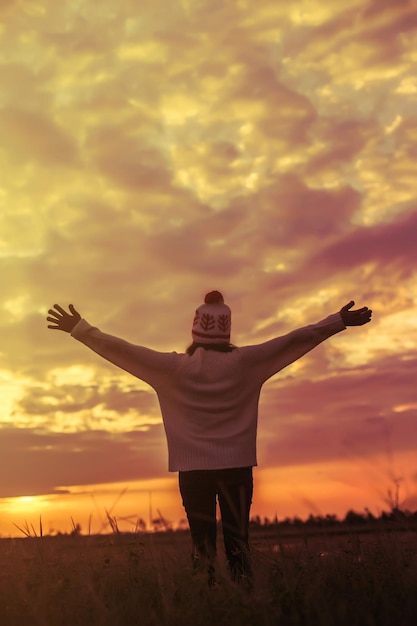 Foto volledige lengte van vrouw die tijdens de zonsondergang op het veld tegen de hemel staat