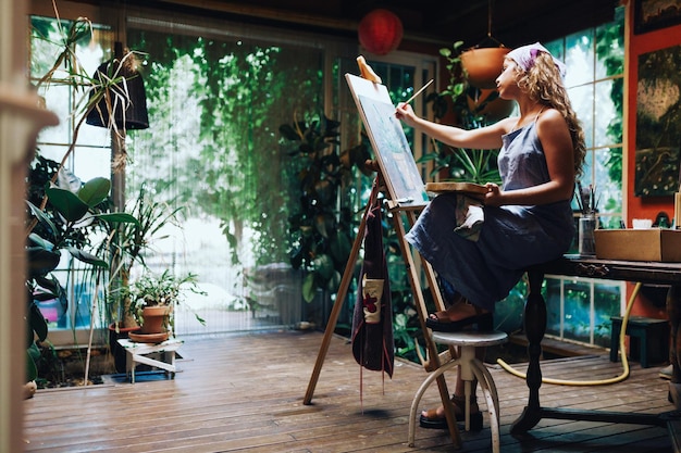 Foto volledige lengte van vrouw schilderij op easel