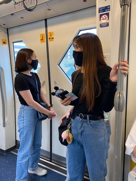 Foto volledige lengte van vrouwen die een masker dragen en in de trein staan