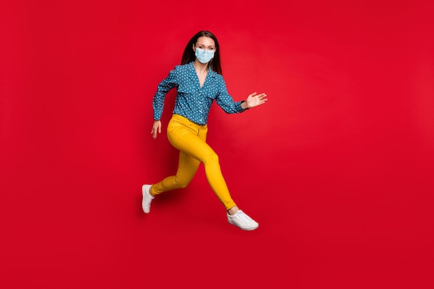 Volledige lengte weergave van aantrekkelijk fit vrolijk meisje springen met actieve beweging dragen masker geïsoleerd felrode kleur achtergrond