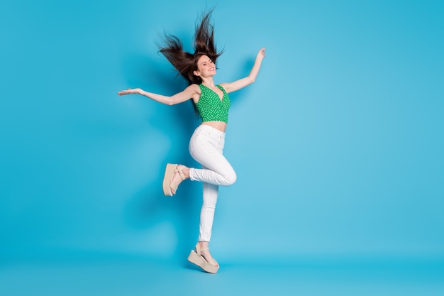 Volledige lichaamsfoto van openhartige inhoud charmant meisje springen genieten verheugen lucht vliegen kapsel klap houden handen opsteken draag goed uitziende outfit schoenen geïsoleerd over blauwe kleur achtergrond