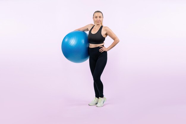 Volledige lichaamslengte shot atletische en sportieve senior vrouw met fitness bal uitoefenen op geïsoleerde achtergrond Gezonde actieve en lichaamsverzorging levensstijl na pensionering Slagkracht