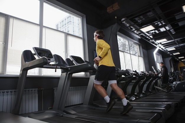 Volledige opname van een man die cardiotraining doet in de sportschool die op de loopband loopt