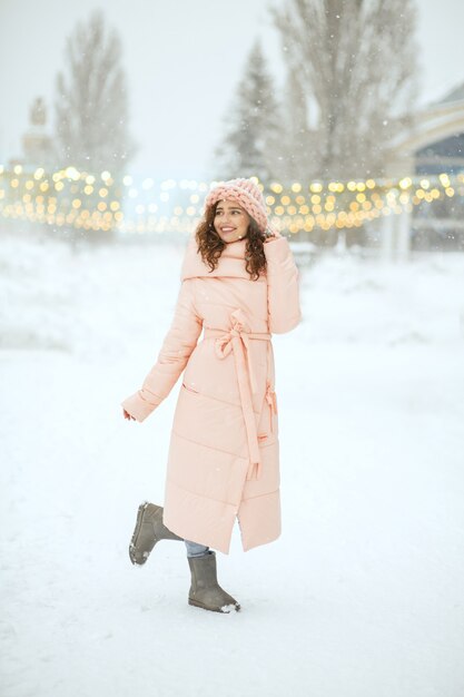 Volledige opname van een vrolijk brunette meisje dat bij sneeuwweer loopt