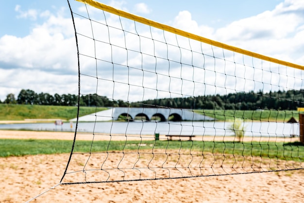 Volleyball court with net on sand near river.