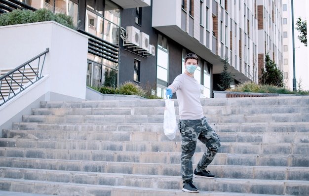 Volunteer carrying necessities for citizens in home self isolation.Young Man with bag of groceries during Corona virus Pandemic.Town in quarantine due to Covid-19 flue infection