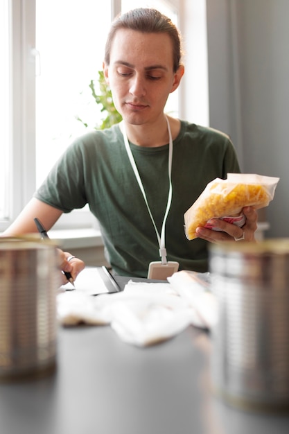 Photo volunteer checking food donations list made for charity