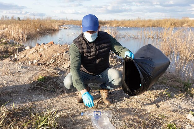 Un volontario raccoglie bottiglie di plastica vuote ecologia e ambiente