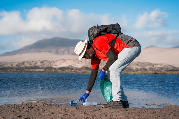 Волонтер собирает пластиковые отходы на пляжеx9