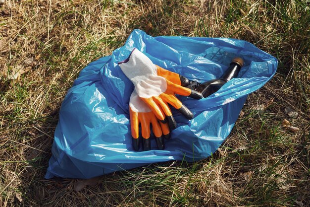 A volunteer and eco activist collects garbage in bags, in the forest, close-up. Recycling of plastic waste, environmental protection. Protecting the planet from debris. Ecology concept.